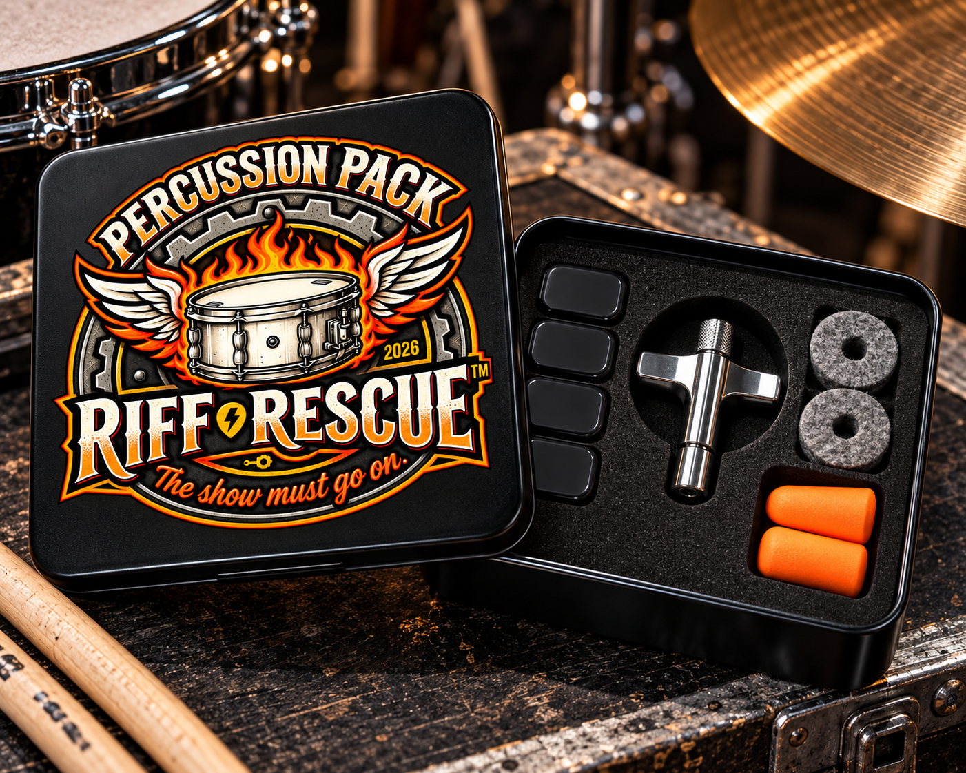 The Percussion Pack square tin open beside a drum kit, showing four black silicone dampening pads, a chrome die-cast drum key, two gray cymbal felts, and a pair of orange earplugs in fitted foam.
